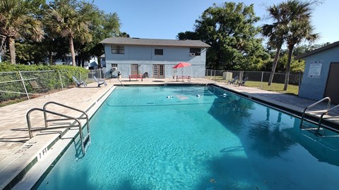 A swimming pool with a diving board and a building in the background.