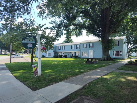 A sign for a local car dealership is on a post next to a sidewalk.