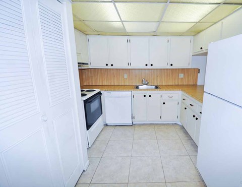 A kitchen with white cabinets and a white refrigerator.
