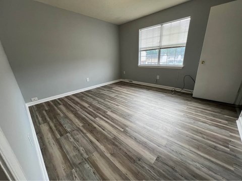 A room with wooden flooring and a window with blinds.
