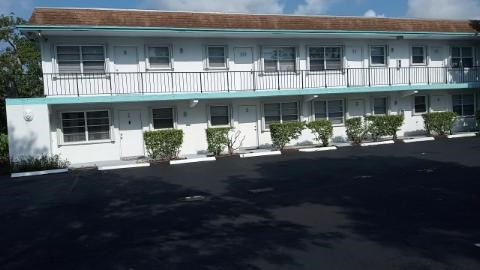 A white building with a balcony and plants in front.