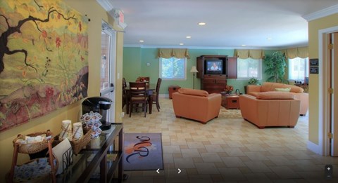 A living room with a painting on the wall and a television.