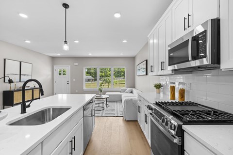 A modern kitchen with white cabinets and black appliances.