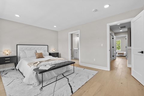 A bedroom with a large bed and a bench in the middle of the room.