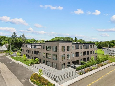 A modern building with a green roof and a parking lot in front.