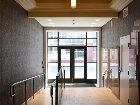 A hallway with a black and white checkered wall and a glass door.
