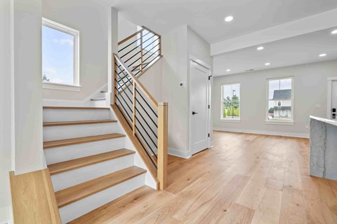A spacious hallway with a wooden staircase and a marble counter.