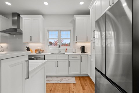 A modern kitchen with white cabinets and a large stainless steel refrigerator.