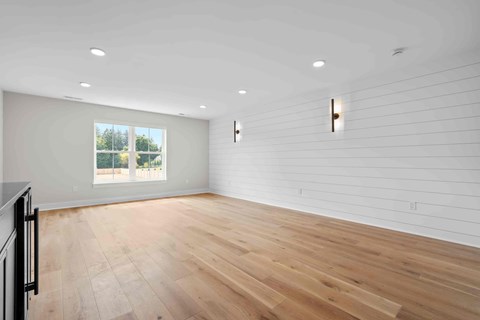 A spacious room with wooden flooring and white walls.