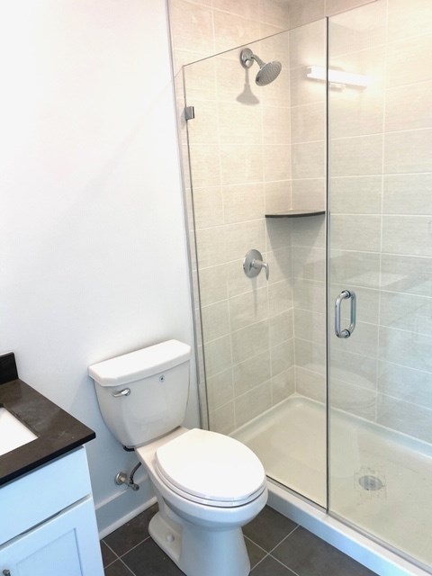 A white toilet in a bathroom with a walk-in shower.