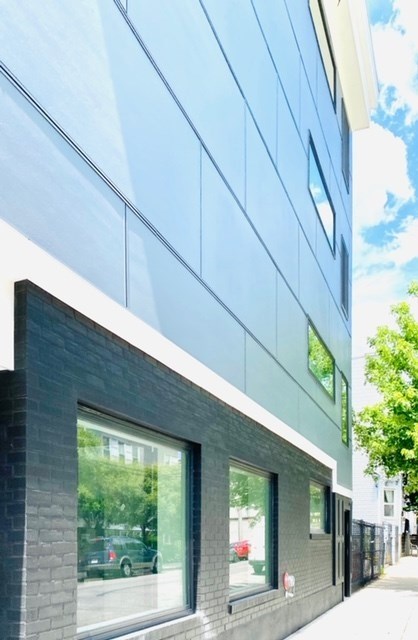 A modern building with a glass facade and a dark grey base.
