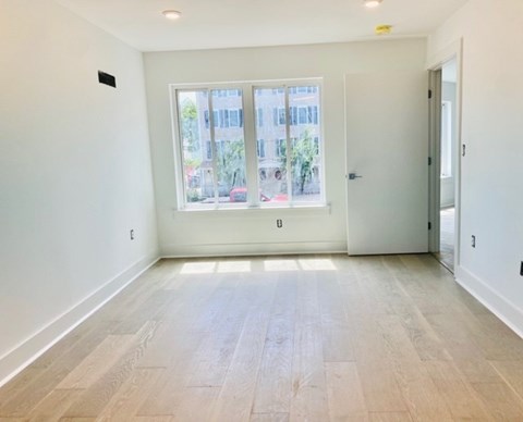 A room with a large window and wooden flooring.