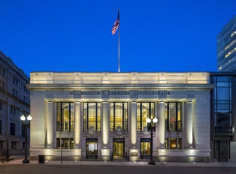 The front of the Mechanics and Farmers Savings Bank building is shown at dusk.