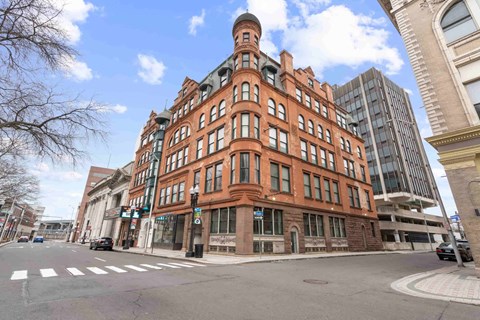 A large red brick building with a tower on the corner of a street.