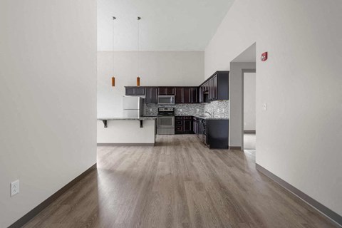 A kitchen with a white wall and a wooden floor.