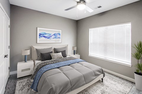 A bedroom with a bed, a ceiling fan, and a painting on the wall.
