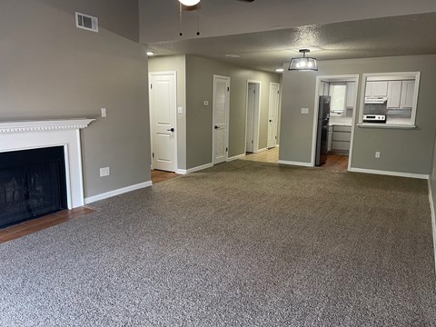A living room with a fireplace and grey carpet.
