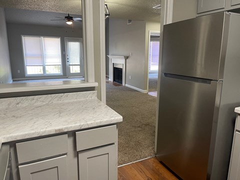 A kitchen with a marble counter top and a stainless steel refrigerator.