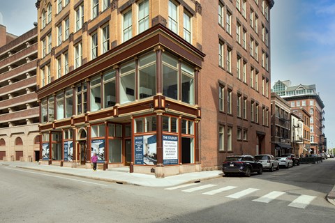 A street view of a building with a large glass window and a sign that says "RENT".