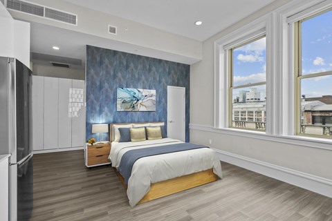 A bedroom with a bed, nightstand, and a painting on the wall.