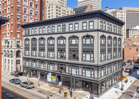 A large, old building with many windows is in the middle of a city street.