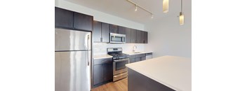 A modern kitchen with dark brown cabinets and stainless steel appliances.
