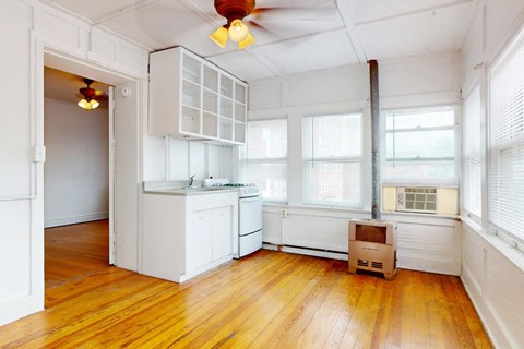 A kitchen with white cabinets and a wooden floor.