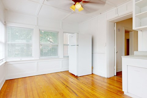 A room with a white ceiling fan and wooden floors.