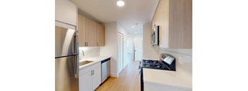 A kitchen with a refrigerator, sink, and cabinets.