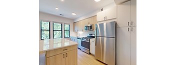 A modern kitchen with a stainless steel refrigerator and wooden cabinets.