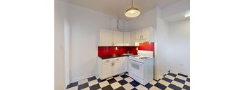 A kitchen with white cabinets and a red backsplash.