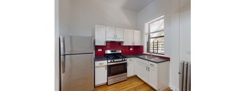 A kitchen with white cabinets and a red backsplash.