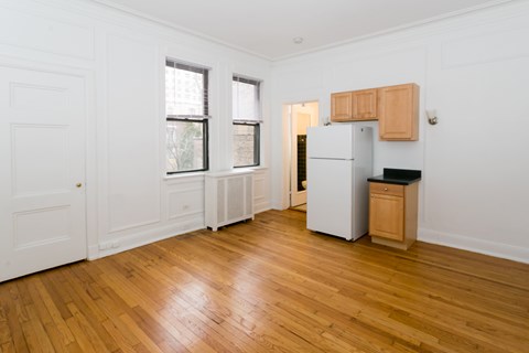 A kitchen with a white fridge and wooden floors.