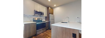 A kitchen with a white counter top and wooden cabinets.