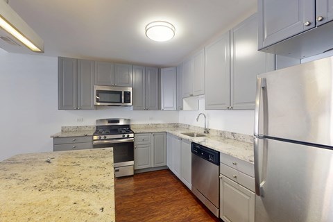 A kitchen with a stainless steel refrigerator, microwave, oven, and sink.