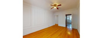 A room with a ceiling fan and wooden floors.