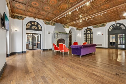 A room with a purple couch and red chairs.