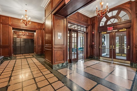 A hallway with a chandelier and a checkered floor.