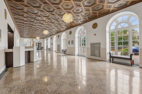A spacious lobby with a marble floor and a patterned ceiling.