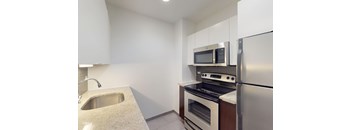 A kitchen with a sink, stove, oven, and microwave.