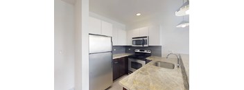 A kitchen with a granite counter top and stainless steel appliances.