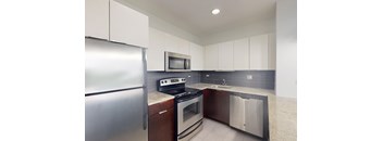 A modern kitchen with a stainless steel refrigerator, microwave, oven, and dishwasher.