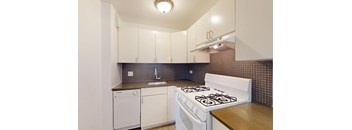 A white gas stove is in a kitchen with white cabinets.