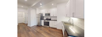A modern kitchen with white cabinets and a wooden floor.