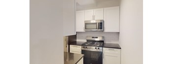 A kitchen with white cabinets and black countertops.