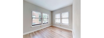A room with two windows and wooden flooring.