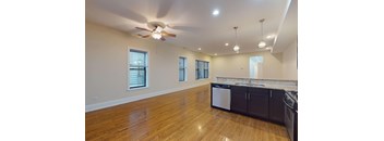 A kitchen with wooden floors and a ceiling fan.