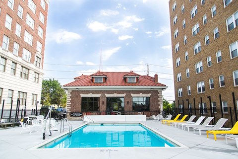 A pool with a red roofed building behind it.