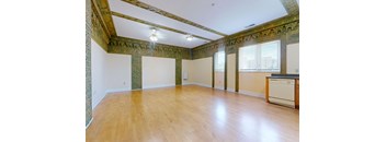 A room with wooden floors and a wall with green and gold decorations.