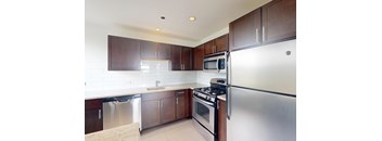 A kitchen with a stove, refrigerator, and microwave.